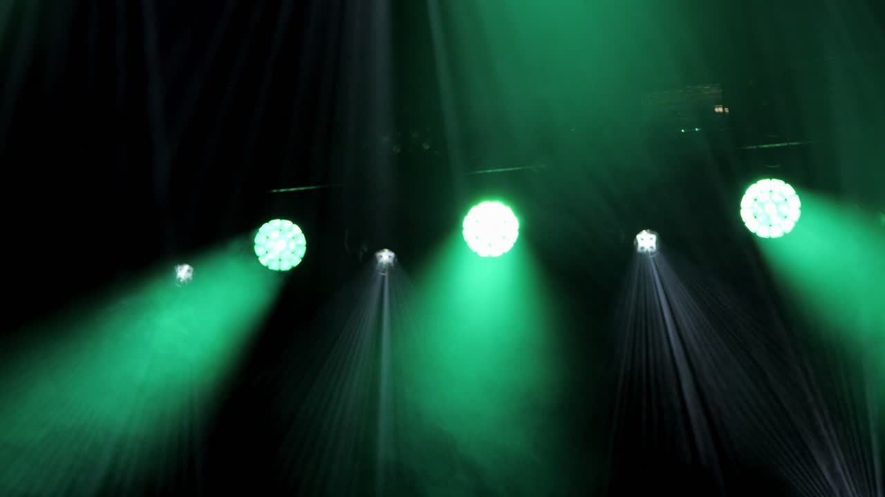 Looking up at green led stage lights as they shine through fog at concert venue in France