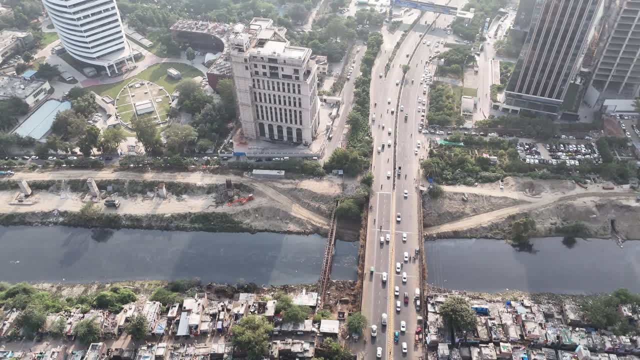 Vista aerea di Film City, Noida Sector 16, che mostra un ponte trafficato su un canale, uffici di alto livello, traffico scorrevole e quartieri densamente popolati, evidenziando la crescita urbana e la connettività