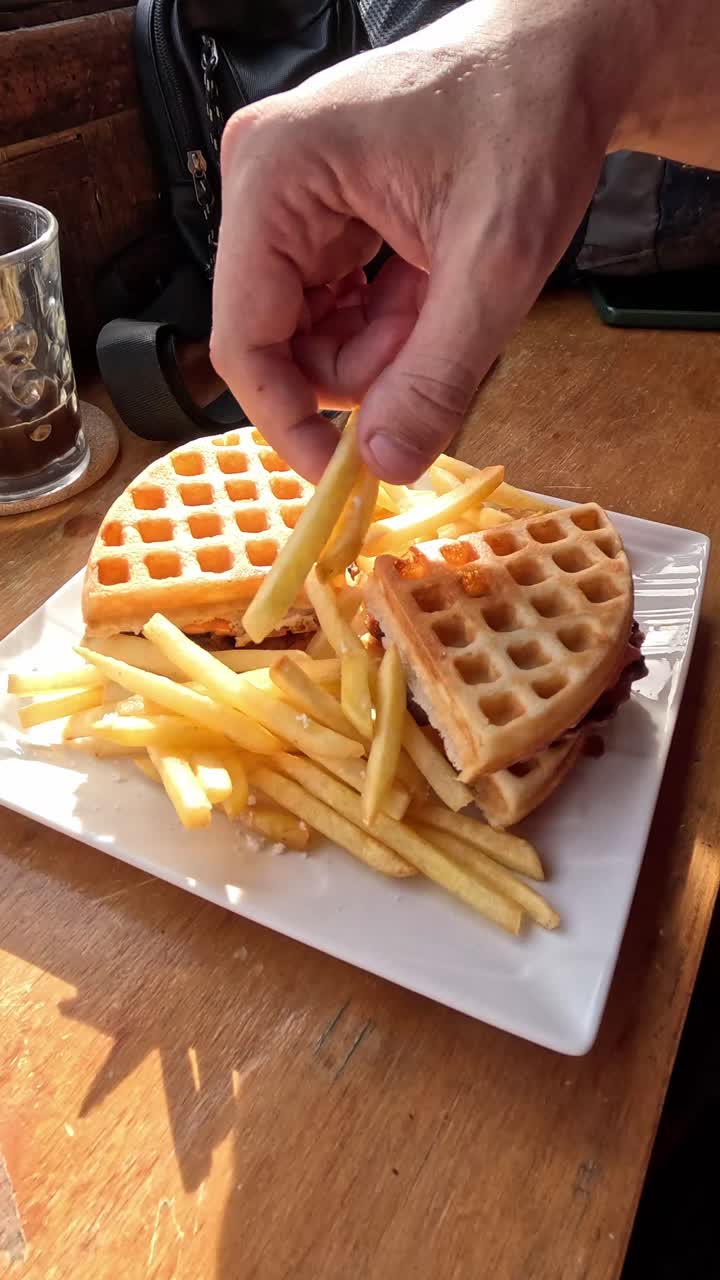 Tracking shot dolly in to a plate of french fries and waffle bathe in golden morning light, eating breakfast meal