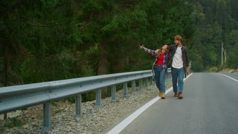 excited travelers hitchhiking mountains highway road. young couple enjoy nature.