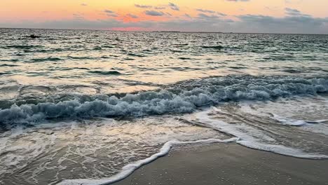 slow motion of ocean waves rolling onto shore during vibrant sunset