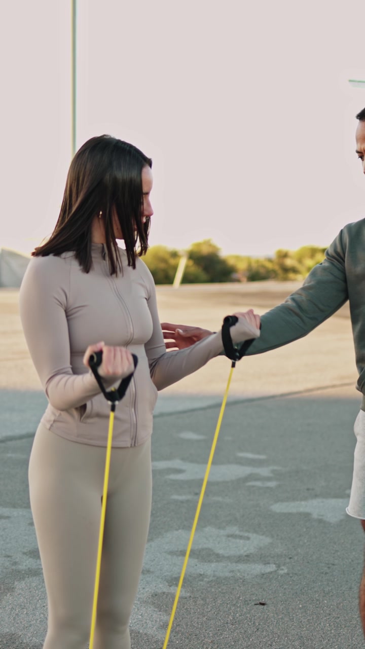 Personal Trainer Assisting Woman with Resistance Band Exercise