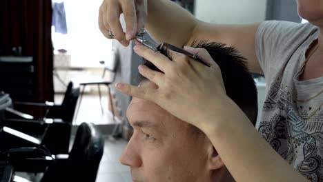 woman hairdresser cuts hair of a man in a beauty salon. she combs her hair with a comb and cuts it with scissors. hair care