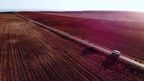 Antenne-Von-Oben-Nach-Unten-Von-Van-Fahrzeugen,-Die-An-Sonnigen-Tagen-Auf-Endlosen-Straßen-Fahren,-Und-Blauem-Ozean-Im-Hintergrund