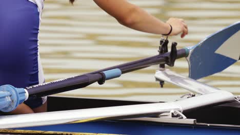 close-up of the girl's hands fixing the oar to the clamping mechanism on the single scull