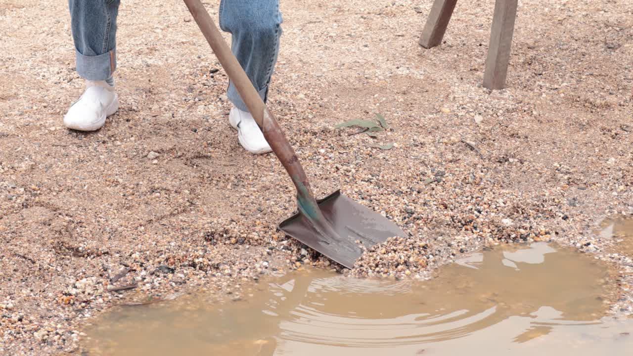 Person digging near water with a shovel