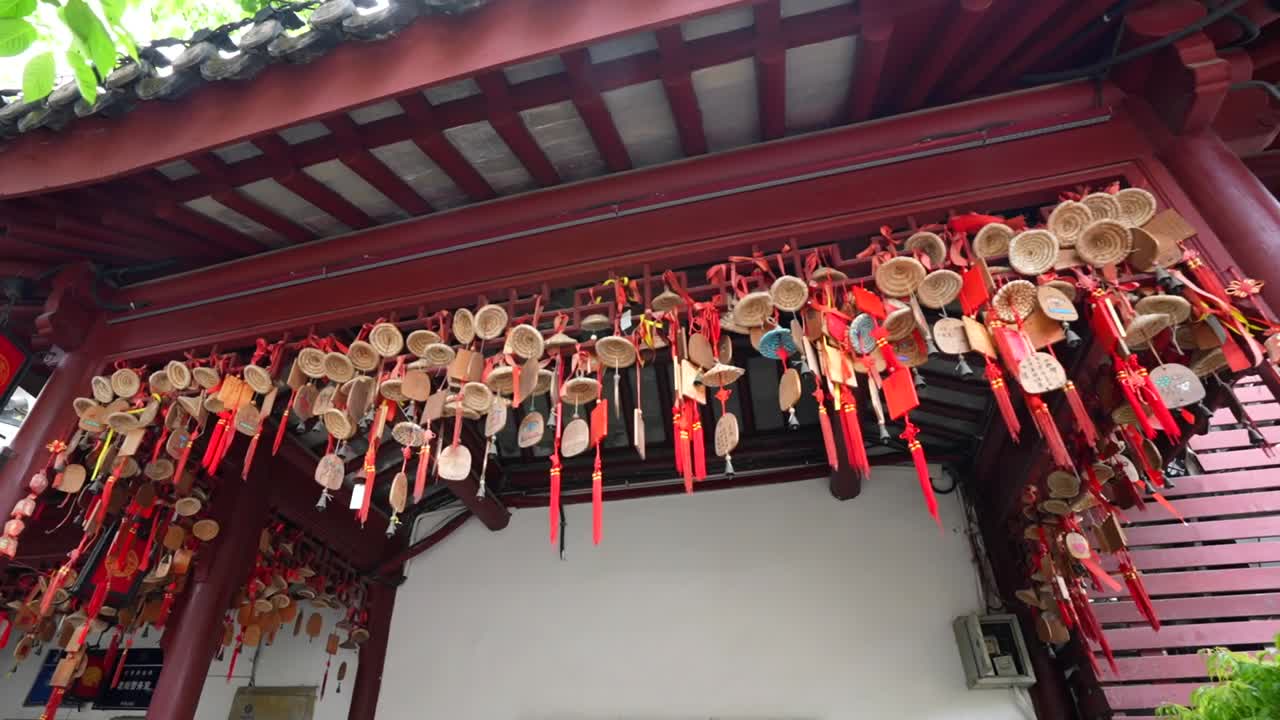 Panning right across Taoist dream catchers and talismans tied with red bows hanging from a rooftop in Qibao. Shanghai, China