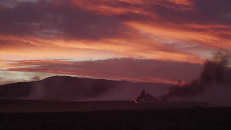 cielo anaranjado dramático durante la puesta de sol sobre el campo de batalla humeante