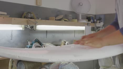 un hombre que hace tablas de surf en su taller