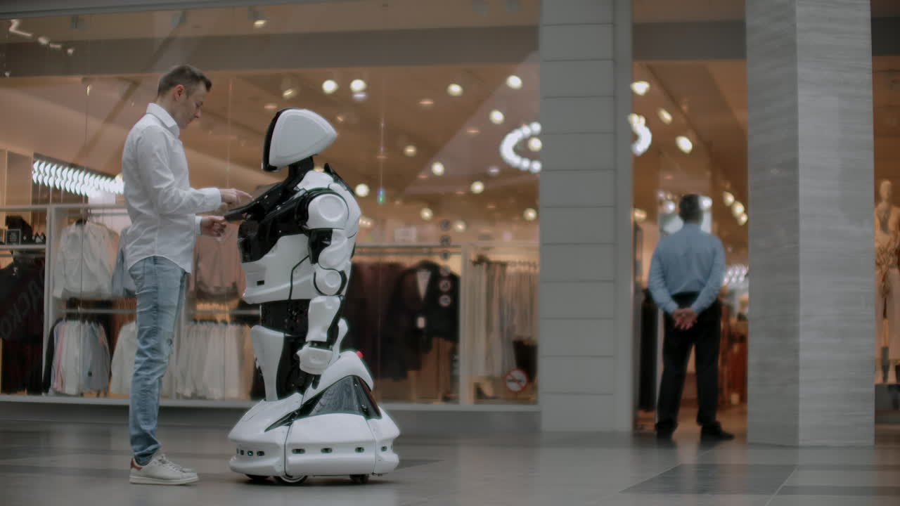 el hombre en el centro comercial se comunica con un asesor robot. tienda moderna y vendedor robot. robot ayuda a un hombre en el centro comercial.