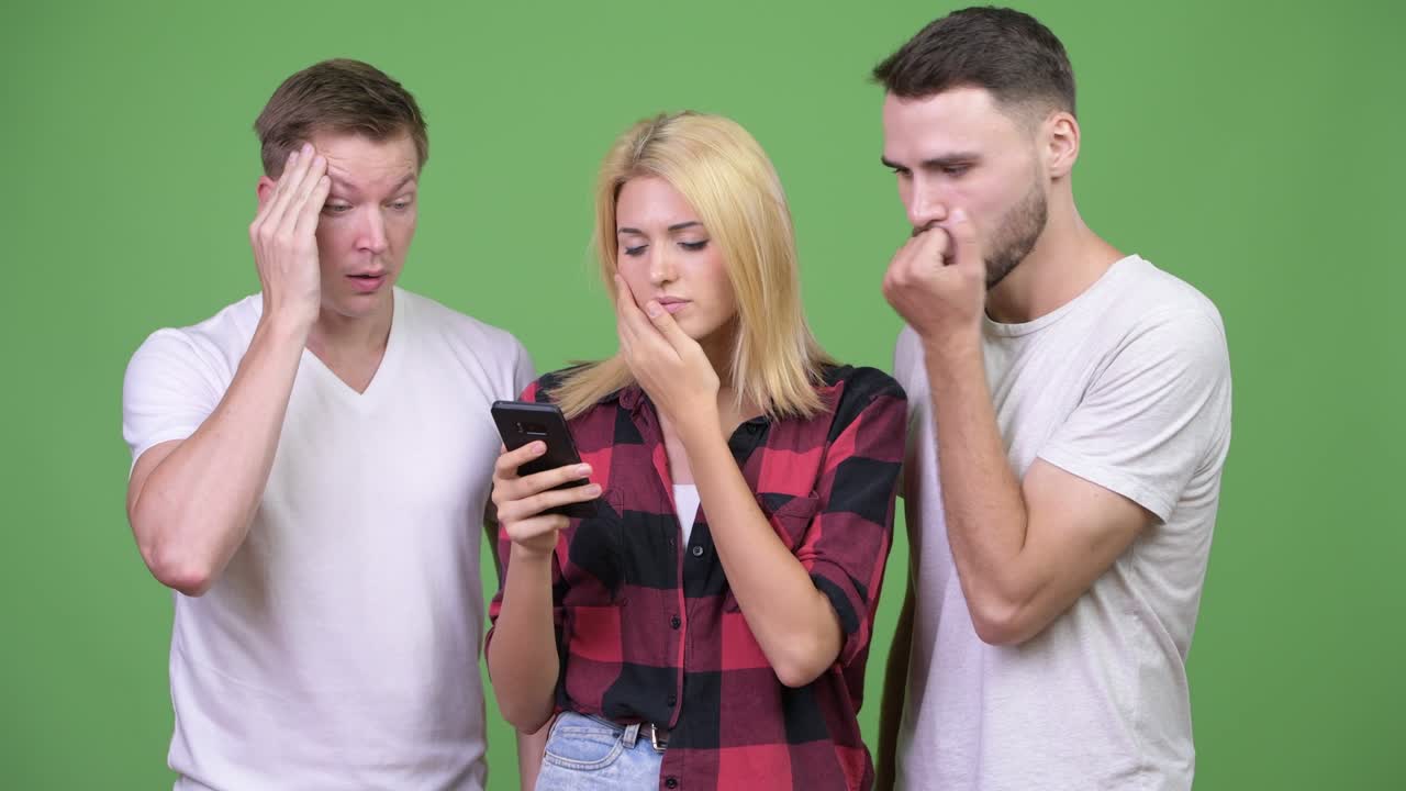 Three young friends using phone together and getting bad news