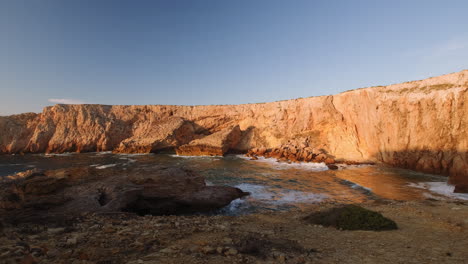 ascend shot of gigantic sun lighting cliff wall with water spots in front