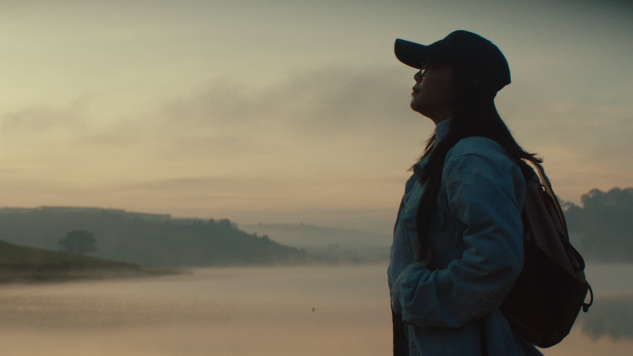 Woman Hiking at Sunrise over a Misty Lake