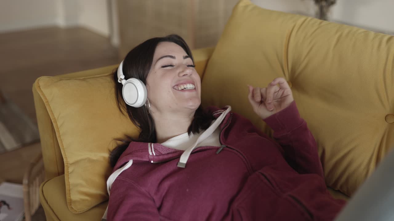 소파 에 누워 음악 을 듣고 있는 젊은 행복 한 여자 의 근접 사진