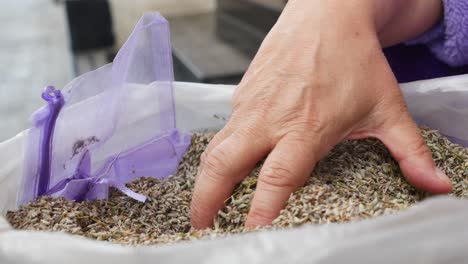 woman's hand reaching into a bag of dried lavender