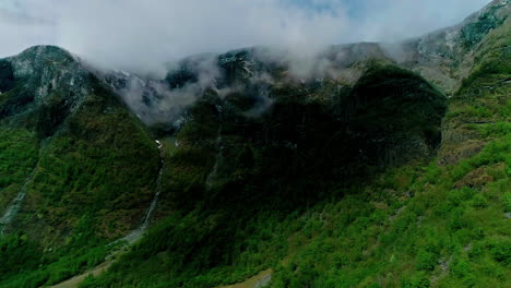 Aerial-shot-of-the-lush-green-hills-with-high-peaks-touching-the-clouds