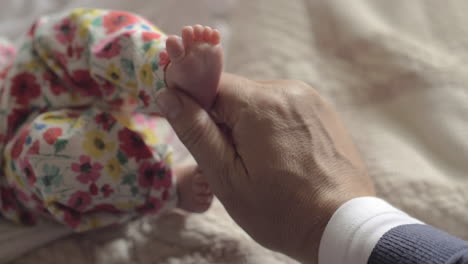 grandad touching feet of baby grandchild