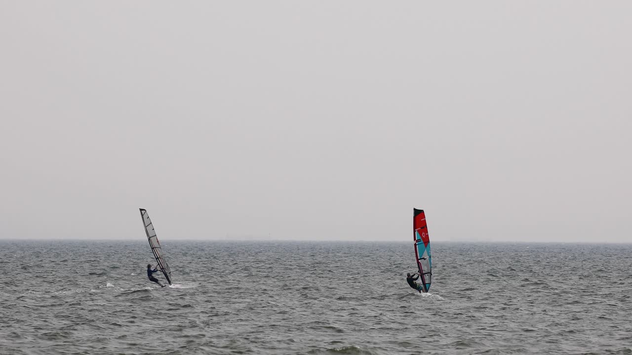 windsurfista se unió a otro windsurfista cruzando el agua en un día nublado en pattaya