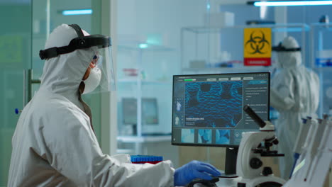 Chemist-in-ppe-suit-typing-on-computer-checking-vaccine-development