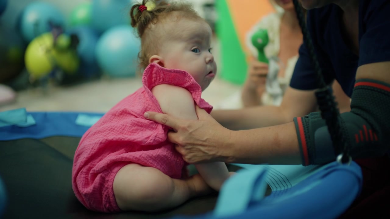 Baby girl resting on rehabilitation equipment, getting specialized care and support from a medical professional