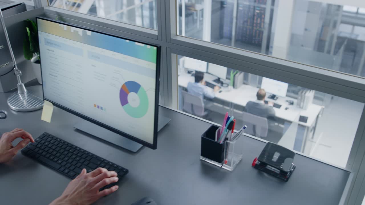 cámara moviéndose de la oficina de espacio abierto personas que trabajan en sus computadoras de escritorio a la mujer de negocios que utiliza la computadora con gráficos y estadísticas. hombres de negocios que trabajan en el primer piso y ejecutivos en el segundo