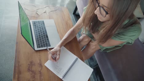 young woman writing list on notebook