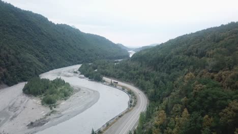 Aerial-view,-drone-flight-along-the-Glenn-Highway-and-the-Matanuska-River-in-the-Chugach-Mountain-Range-of-central-Alaska-on-a-cloudy-summer-day