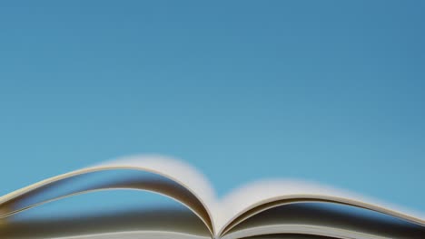 Video-of-open-book-with-navy-cover-on-desk-over-blue-background