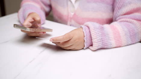 la mano de una mujer de primer plano sostiene un teléfono inteligente y utiliza una tarjeta de crédito bancaria de maqueta para servicios de compras en línea para pagar dinero con tecnología sin efectivo