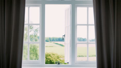 bedroom curtains closing on view of countryside through window