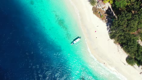 Philippine-traditional-long-boat-anchoring-on-white-sandy-shore-beach-of-tropical-island-washed-by-blue-turquoise-sea-water