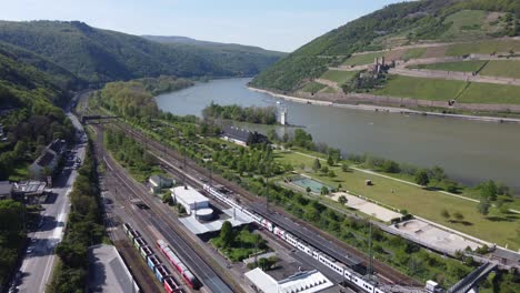 volando sobre la estación de tren de bingen am rhein hacia la torre del ratón y el castillo de burg ehrenfels en el valle del rin medio