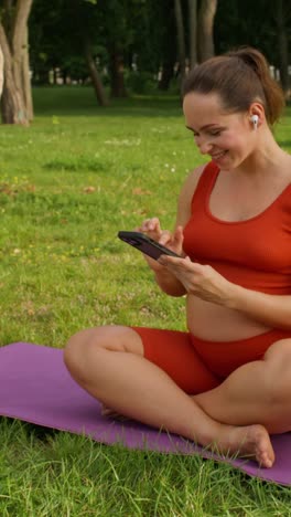 mujer embarazada usando un teléfono inteligente en el parque