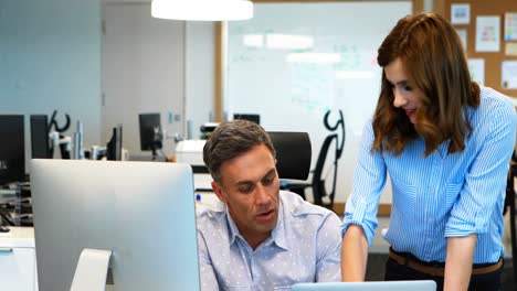 Business-colleagues-working-on-computer-and-laptop-at-desk