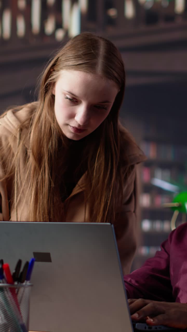 Vertical video diverse students working together on a college assignment at the library
