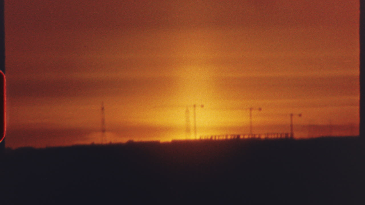 8 mm film - warm orange and red colors dominate the six separate shots of a setting sun, with silhouettes of landscapes and urban structures visible in the foreground