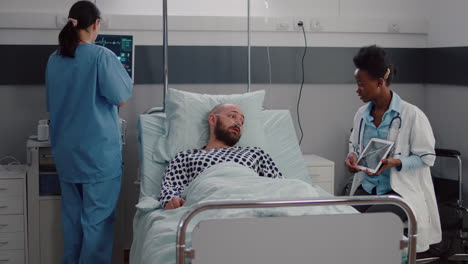 Practitioner-black-doctor-explaining-bones-radiography-to-sick-man-using-tablet-computer