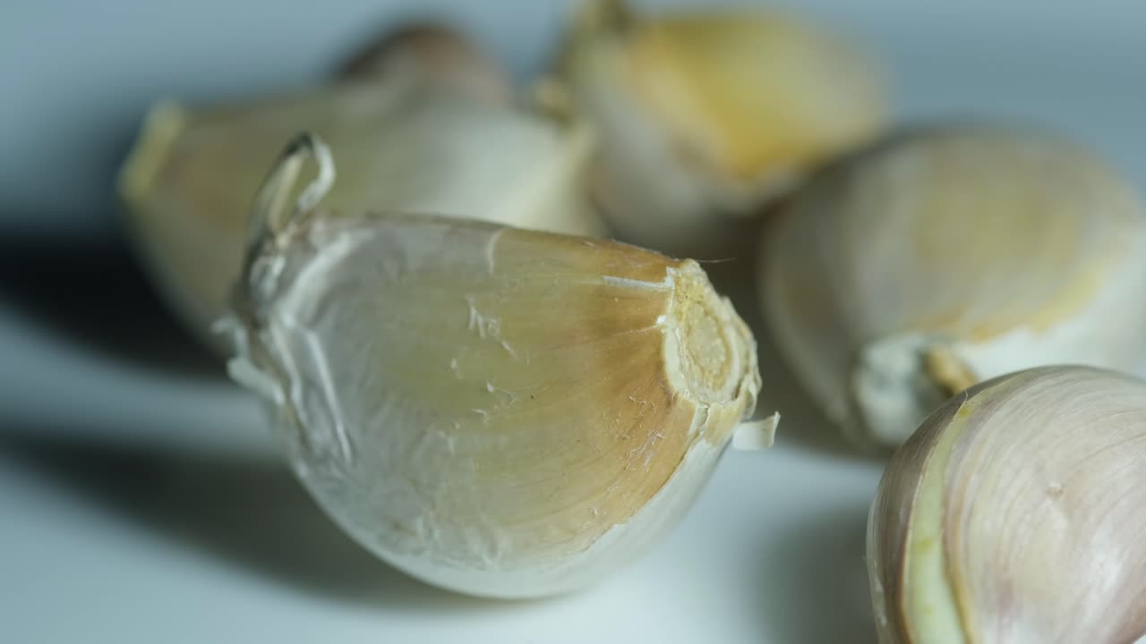 Garlic,Allium sativum, seen moving on a white porcelain plate with other cloves