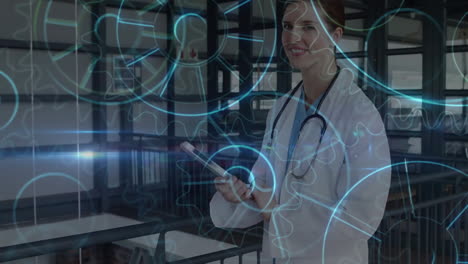 animación de engranajes sobre médico caucásico mujer usando tableta