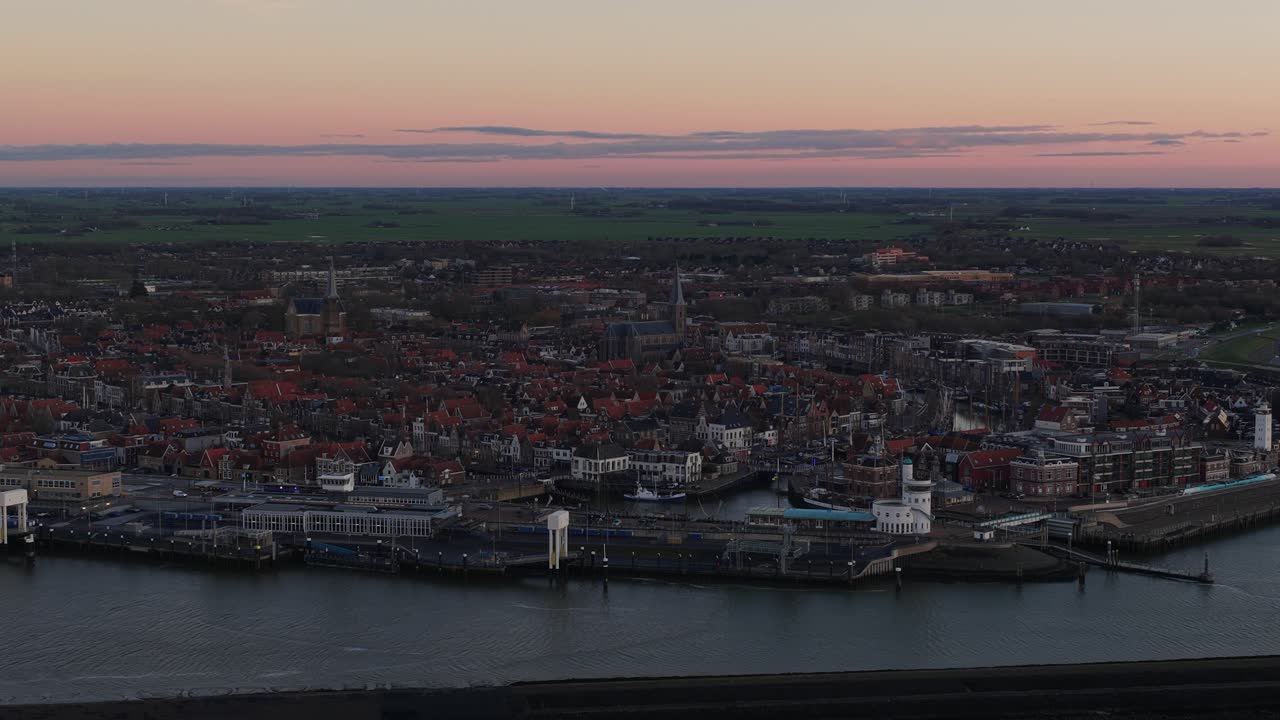 Aerial drone footage of Harlingen along the Wadden Sea, capturing its coastal village skyline, seafront architecture, and the soft evening atmosphere at dusk
