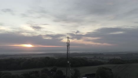 drone aerial view above british rural farm countryside broadcast signal towers at sunrise