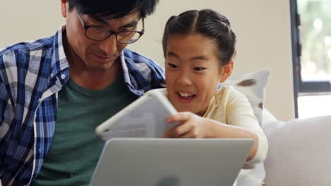 Family-using-digital-tablet-and-laptop-in-living-room-4k