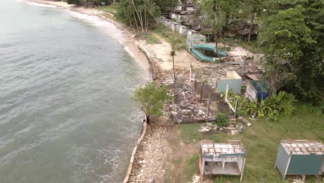 aerial birds eye view descending down shot of a abandoned derelict destroyed beach bungalow resort from the effects of covid 19 on tourism