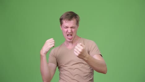 young handsome scandinavian man looking excited against green background