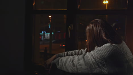 woman sitting by window at night