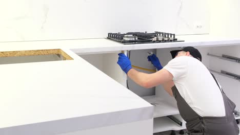 a professional worker installs a new gas stove in the kitchen room