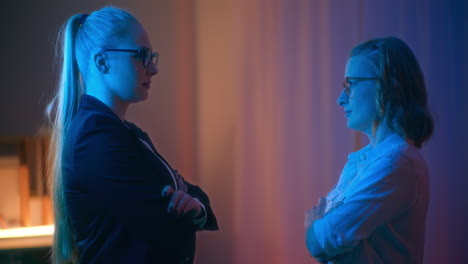 confrontation of two women standing opposite each other in blue light