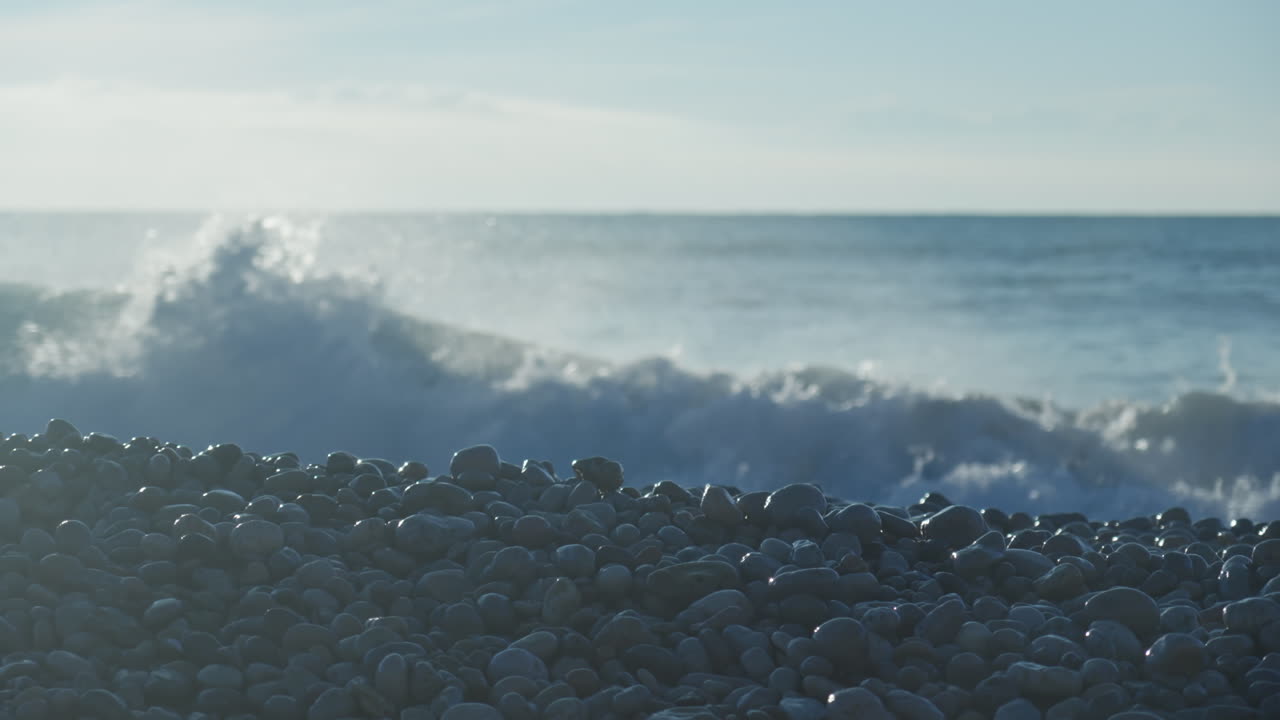 발은 화창한 아침에 배경에서 부서지는 파도와 함께 바위가 많은 해변을 가로지른다