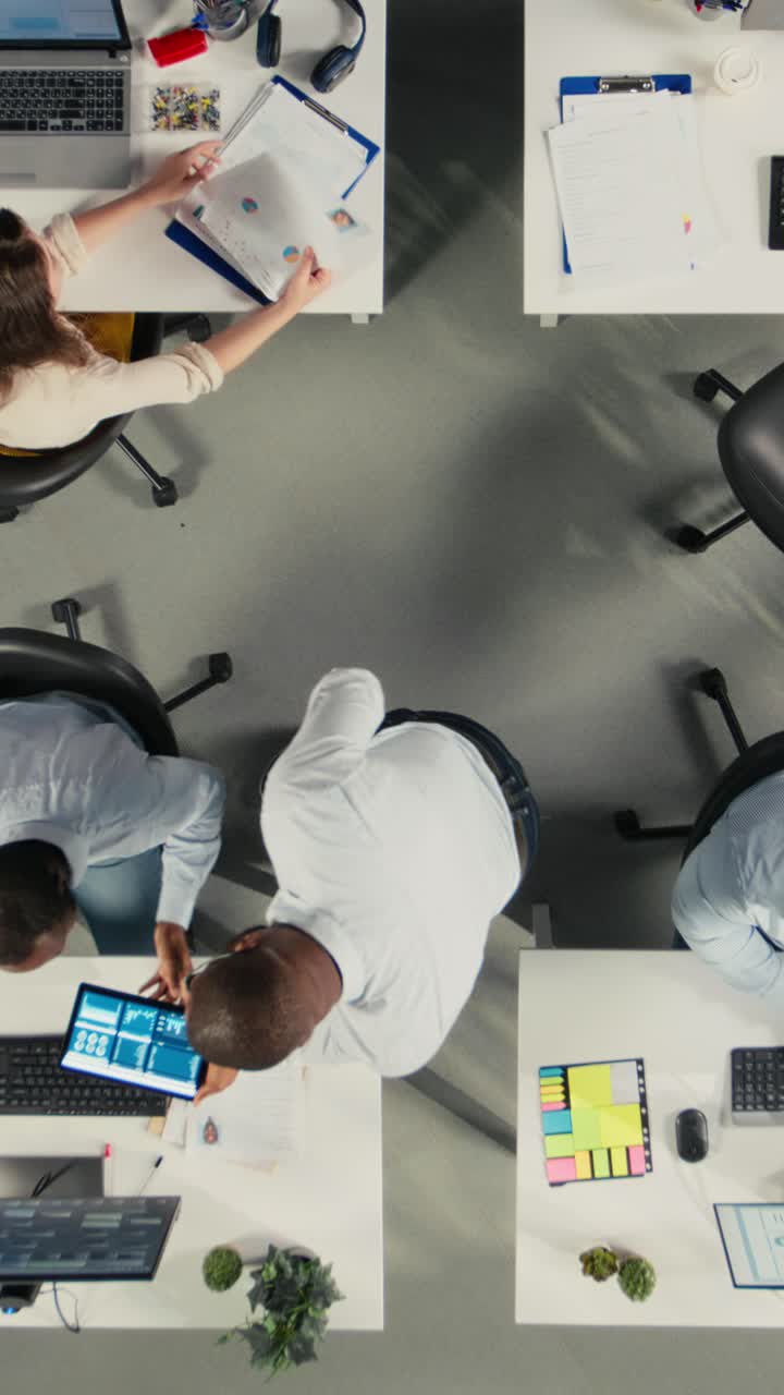 Vertical Video Top down view zoom in of diverse staff in office working on forecasting