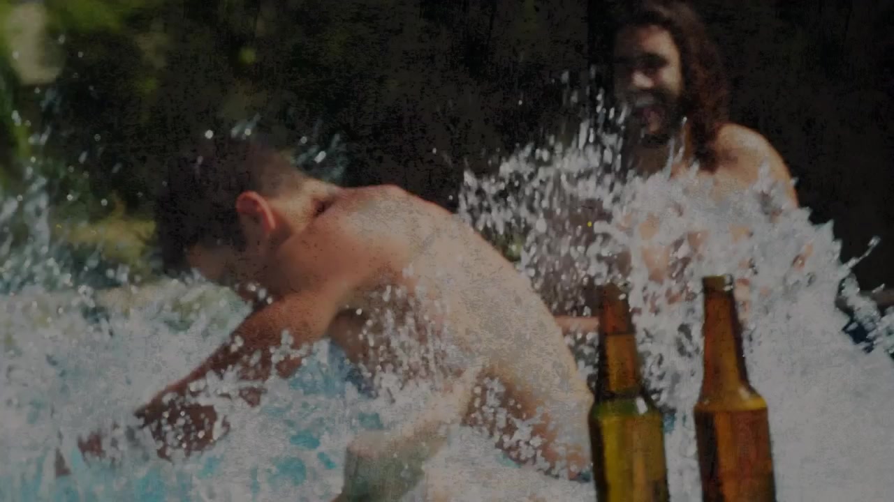 Amigos grabando contenido social, un hombre levanta a una mujer de forma juguetona, pierden el equilibrio y salpican botellas de cerveza.
